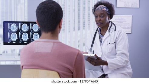 Portrait Of Mid Aged Black Doctor Consulting With Male Patient His Concussion