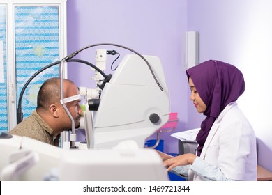 Portrait Of Middle Age Asian Man Having Eye Examinating Check With Digital Optometry Tools With Hijab Female Ophthamologists On Clinic Room -image