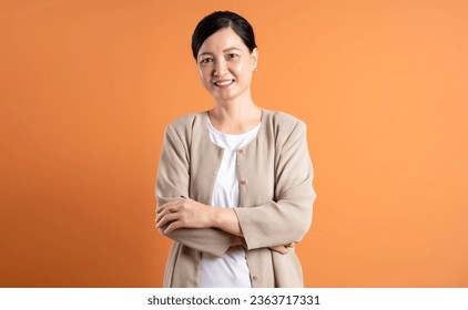 Portrait of middle age Asian woman posing on brown background - Powered by Shutterstock