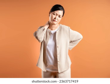 Portrait of middle age Asian woman posing on brown background - Powered by Shutterstock