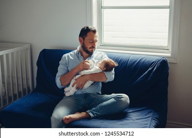 Portrait of middle age Caucasian father feeding newborn baby son daughter with milk. Male man parent holding child on his hands. Authentic lifestyle candid real moment. Single dad family life concept - Powered by Shutterstock