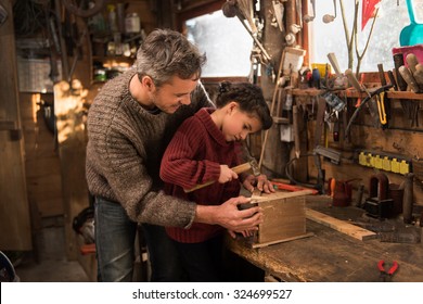 Portrait of a middle age gray hair man with beard working with his little girl in the workshop. They are focused while hammering a nail on a wooden birdhouse.  - Powered by Shutterstock