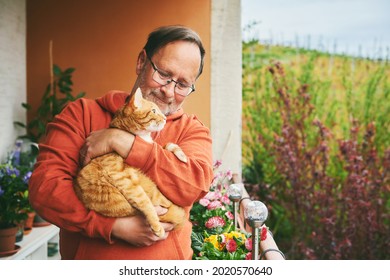 Portrait Of Middle Age Man Holding Cute Ginger Cat, Resting On Small Cozy Balcony