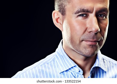 Portrait of a middle age man slightly smiling at camera. Black background.