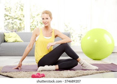 Portrait Of Middle Age  Woman Stretching On A Yoga Mat At Home. 