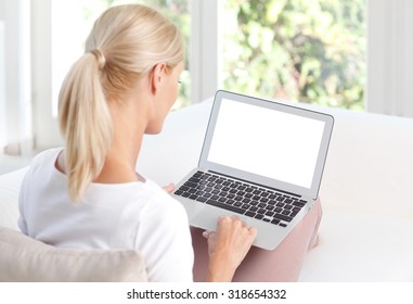 Portrait Of Middle Age Woman Using Her Blank Screen Laptop While Sitting Back To Back On The Sofa At Home.