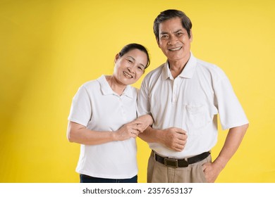 portrait of middle aged asian couple posing on yellow background