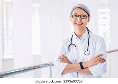 Portrait of middle aged asian female doctor standing in hospital corridor. Nurse general practitioner gynecologist looking at the camera. Family doctor - Powered by Shutterstock