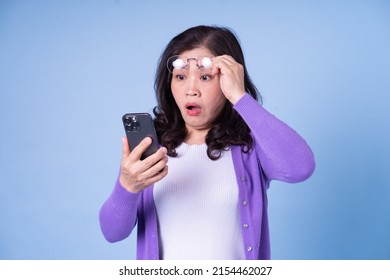 Portrait of middle aged Asian woman using laptop on blue background - Powered by Shutterstock