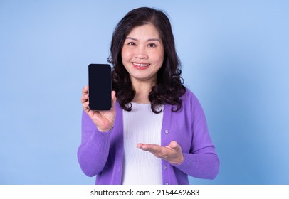 Portrait Of Middle Aged Asian Woman Using Smartphone On Blue Background