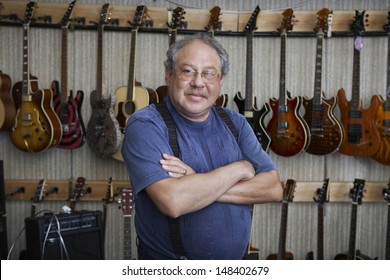 Portrait Of Middle Aged Male Music Store Owner Standing Arms Crossed