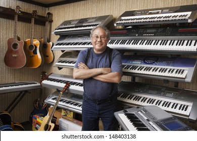 Portrait Of Middle Aged Male Music Store Owner Standing Arms Crossed