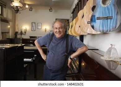 Portrait Of Middle Aged Male Owner Leaning In Music Store