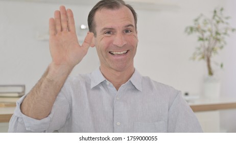 Portrait Of Middle Aged Man Waving On Video Call