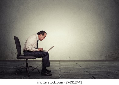 Portrait Middle Aged Man Working On Laptop Sitting On Chair In Empty Office Room