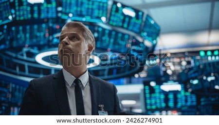 Portrait of a Middle Aged Man Working on the Floor in a Modern Stock Exchange Firm. Specialist Monitoring Companies and Funds, Securities, Derivatives, Investment Products, Bonds on Computer Displays