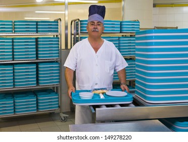 Portrait Of Middle Aged Porter With Plastic Trays In Hospital Kitchen