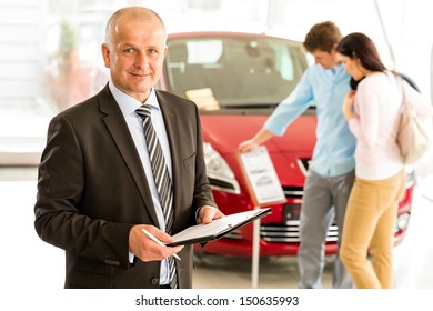 Portrait Of Middle Aged Salesman In Car Retail Store