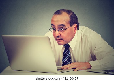 Portrait Middle Aged Shocked Business Man Sitting In Front Of Laptop Computer Looking At Screen Isolated On Gray Wall Background. Funny Face Expression Emotion Feelings Problem Perception Reaction