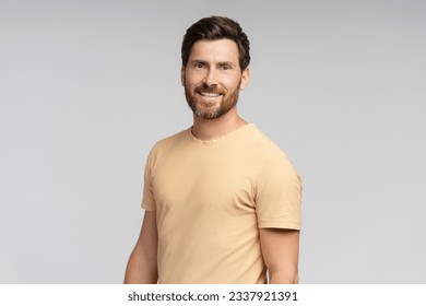 Portrait of middle aged smiling bearded man looking at camera isolated on gray background. Confident modern hipster with stylish hair after barbershop service