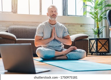 Portrait of middle aged sport man doing yoga and fitness at home using laptop