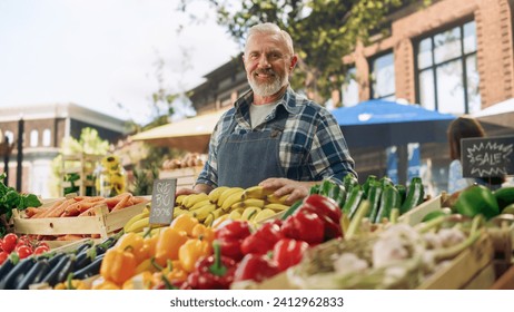 Portrait of a Middle Aged Street Vendor Working at a Farmers Market Stall with Fresh Organic Agricultural Products. Businessman Looking at Camera and Smiling. Farmer Selling Eco Fruits and Vegetables