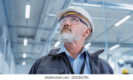 Portrait of a Middle Aged, Successful Male Engineer in White Hard Hat and Safety Glasses, Standing at Electronics Manufacturing Factory. Heavy Industry Specialist Posing for Camera. Low Angle Shot. - Powered by Shutterstock