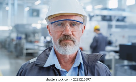 Portrait of a Middle Aged, Successful Male Engineer in White Hard Hat and Safety Glasses, Standing at Electronics Manufacturing Factory. Heavy Industry Specialist Posing for Camera. - Powered by Shutterstock