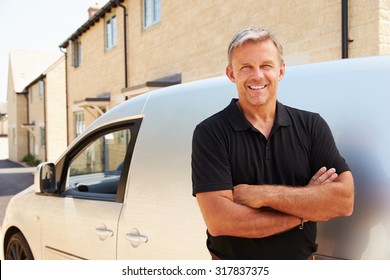 Portrait of middle aged tradesman standing by his van