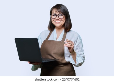 Portrait of middle aged woman in apron with laptop on white background. - Shutterstock ID 2240774601