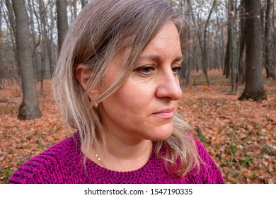 Portrait Of Middle Aged Woman In Autumn Forest. Girl Does Not Look At Camera On Blurred Background. Thought, Meditation Or Doubt Expression. Relax Or Other Mental Psychology Concept