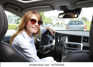 Portrait Of Middle Aged Woman Driving Car And Looking Back Over Her Shoulder. 