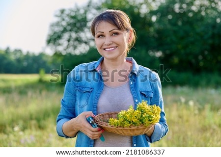 Portrait of middle aged woman with fresh cut flowers of St. John's wort plant