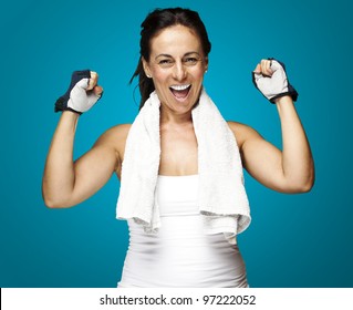 Portrait Of A Middle Aged Woman Gesturing A Win Symbol Over A Blue Background