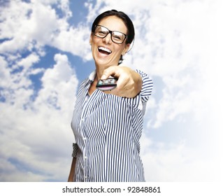 portrait of a middle aged woman using tv control with a cloudy sky as a background
