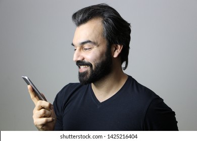 Portrait Of A Middle Eastern Man Using Mobile Phone Technology And Smiling 