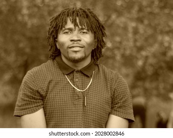 Portrait Of A Middle-aged African Man With A Traditional Hairstyle. Representative Of The Negroid Race, Originally From Cameroon. Monochrome Photography With Sepia Effect.