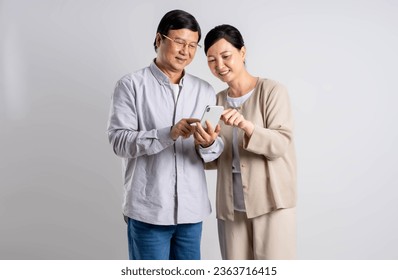 Portrait of middle-aged Asian couple using phone  on a white background - Powered by Shutterstock