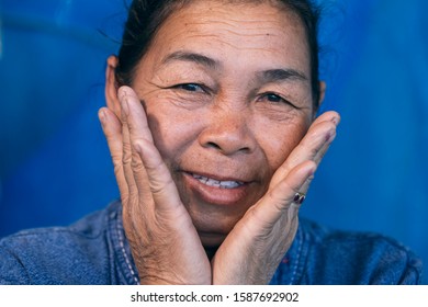 Portrait Of Middle-aged Asian Woman Smiling With Blue Background, Close-up