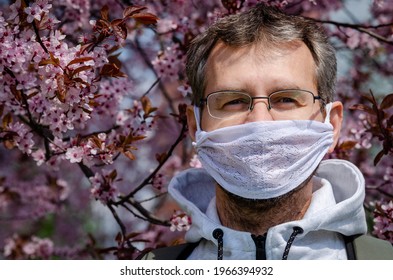 Portrait Of A Middle-aged Man In A Self Made Mask Under A Cherry Tree In Bloom During Covid-19 Pandemic