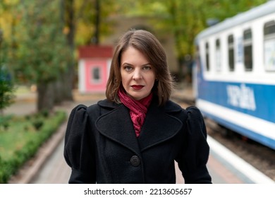 Portrait Of Middle-aged Woman In Black Coat Against Of Retro Train. Aristocrat Lady Waiting For Train On Platform