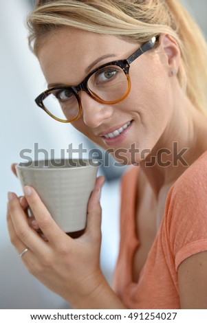 Portrait of middle-aged woman with eyeglasses drinking tea