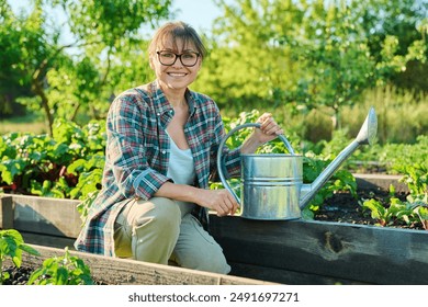 Portrait of middle-aged woman with watering can in vegetable garden - Powered by Shutterstock