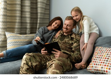 Portrait of military family sitting on the couch at home and watching photo album with happy faces. Happiness concept  - Powered by Shutterstock