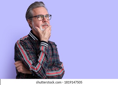 Portrait Of Minded Pensive Curious Old Man In Contemplation, Have Spectacles Touch Chin Isolated Over Purple Background, Look At Camera