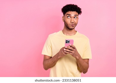 Portrait of minded thoughtful guy with afro hair wear stylish t-shirt hold smartphone look empty space isolated on pink color background - Shutterstock ID 2331138051
