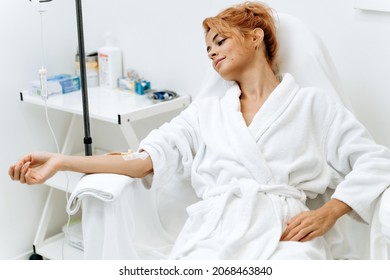 Portrait of mindful woman sitting in armchair and closed eyes while receiving IV infusion with vitamins. Cosmetology and medicine concept 