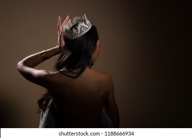 Portrait of Miss Pageant Beauty Contest in open back Evening fur Gown dress with sparkle light Diamond Crown, Asian Woman fashion make up black hair style, turn back side rear view no face