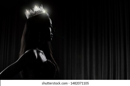 Portrait of Miss Pageant Beauty Contest in sequin Evening Ball Gown long dress with sparkle light Diamond Crown, silhouette low key exposure with curtain, studio lighting dark background dramatic - Shutterstock ID 1482071105