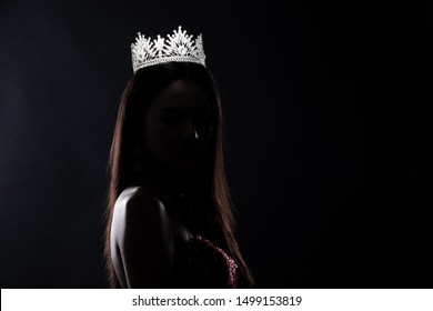 Portrait of Miss Pageant Beauty Contest in sequin Evening Ball Gown long dress with sparkle light Diamond Crown, silhouette low key exposure with curtain, studio lighting dark background dramatic - Shutterstock ID 1499153819